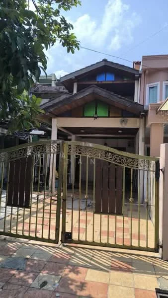 Exterior type: semi-detached house; features: gated entrance, stone-paved driveway, wooden front door, sloped roof with wooden beams, green and blue accent colors on facade, front porch area, manicured landscaping, mature trees, two-storey structure, visible windows with decorative frames; style: traditional.