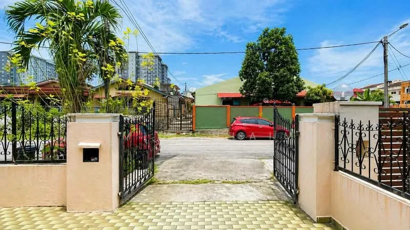 Exterior type: linked terrace house; features: gated entrance, manicured lawn, paved walkway, surrounded by greenery, street view, visible cars parked on street, residential neighborhood, fence with decorative wrought iron, single-storey building in background, multi-storey buildings in background; style: modern.