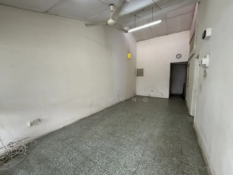 Room features: white painted walls, grey tiled flooring, ceiling fan, wall-mounted clock, doorway leading to another room, electrical outlets, exposed wiring.