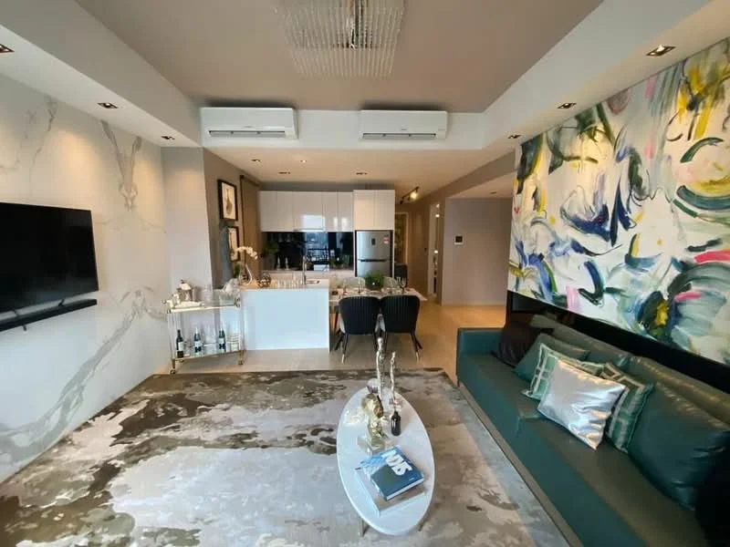 Living features: sofa in dark green, coffee table, area rug with abstract pattern, wall-mounted TV, recessed downlights, 2 wall-mounted split AC units, decorative wall with abstract painting, white painted walls, light wood flooring; style: modern. Kitchen features: white cabinetry, stainless-steel fridge, built-in oven, ceramic cooktop, white countertop, bar stools, open shelving, kitchen island; style: modern.