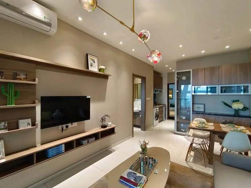 Living features: wall-mounted TV, wooden TV console, decorative wall shelf, 5-blade ceiling fan with light, recessed LED downlights, light fixture with glass pendant lights, cream painted walls, white tiled flooring, open-plan layout with dining area, decorative plant on shelf, coffee table, dining table with place settings, grey upholstered dining chairs; style: modern. Kitchen features: stainless-steel fridge, built-in washing machine, black countertop, wood cabinetry, glass-front upper cabinets, kitchen island, open shelving, ceramic tile backsplash; style: modern.