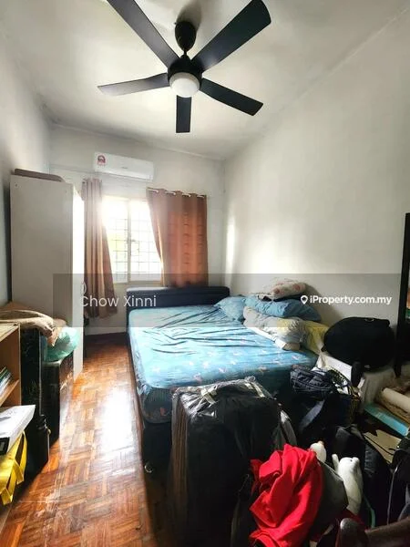 Bedroom features: queen-size bed with blue bedding, wooden flooring, white painted walls, ceiling fan with 5 blades, window with sheer curtains, built-in wardrobe, decorative pillows, stacked bags and boxes.
