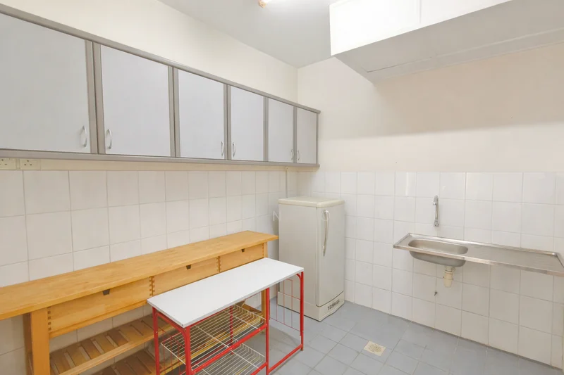 Kitchen features: white tiled walls, grey cabinetry, wooden countertop, stainless-steel sink, chrome faucet, white fridge, grey tiled flooring, open shelving, under-counter storage, fluorescent ceiling light.
