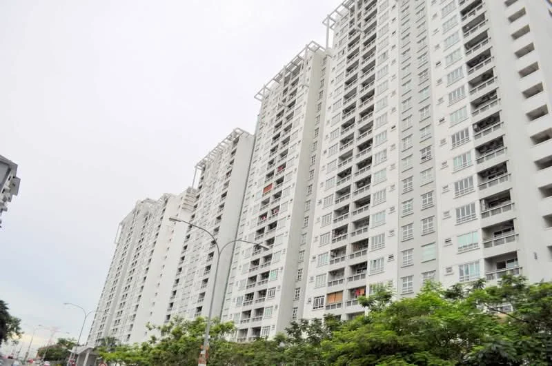Exterior type: high-rise condominium; features: white painted facade, glass balcony railings, multiple storeys, exposed concrete, large windows, balconies on each unit, surrounded by greenery, urban setting; style: modern.