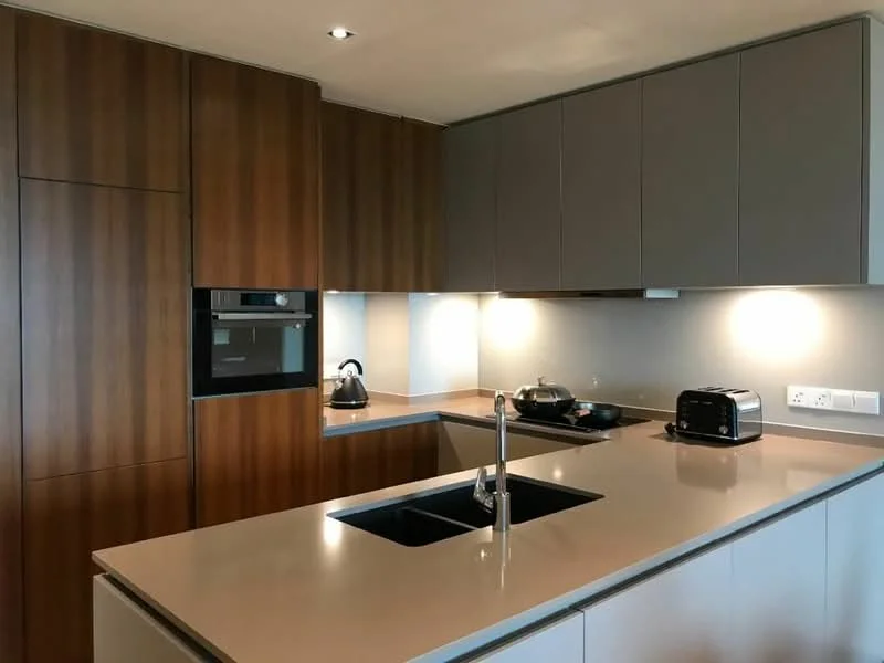Kitchen features: brown wood cabinetry, grey upper cabinets, quartz countertop, single-bowl stainless-steel sink, chrome pull-down faucet, built-in oven, stainless-steel kettle, stainless-steel toaster, induction cooktop, recessed LED downlights, backlit wall, smooth surface backsplash; style: modern.