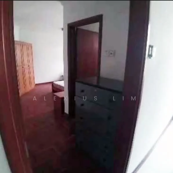 Room features: wooden flooring, brown wooden door, built-in wardrobe with wooden doors, chest of drawers, white walls, light switch, door frame, visible bed in background.
