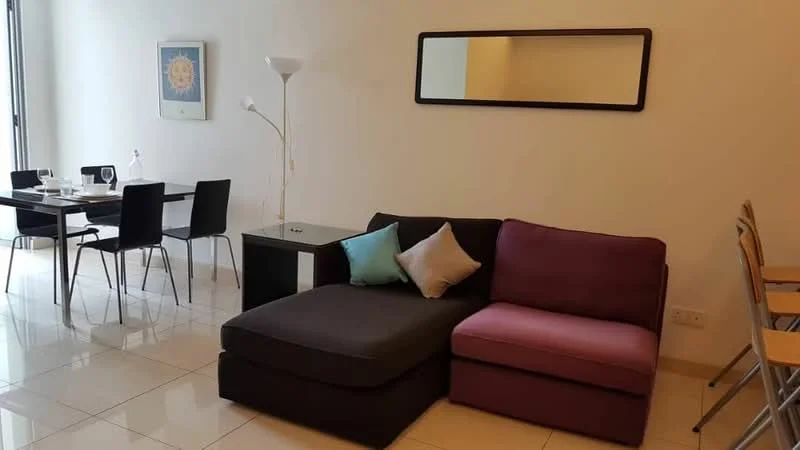 Living features: L-shape sectional sofa in grey and purple, decorative cushions, floor lamp, coffee table, wall-mounted mirror, tile flooring, neutral painted walls, large windows with natural light; style: modern. Dining features: 4-seater dining table, black dining chairs, table setting with plates and glasses; style: modern.