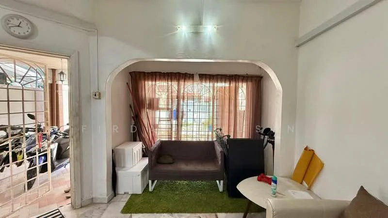 Living features: white painted walls, marble flooring, sofa in dark color, green area rug, large window with sheer curtains, decorative wall clock, small side table, bicycle visible in background, storage boxes, two yellow cushions; style: modern.