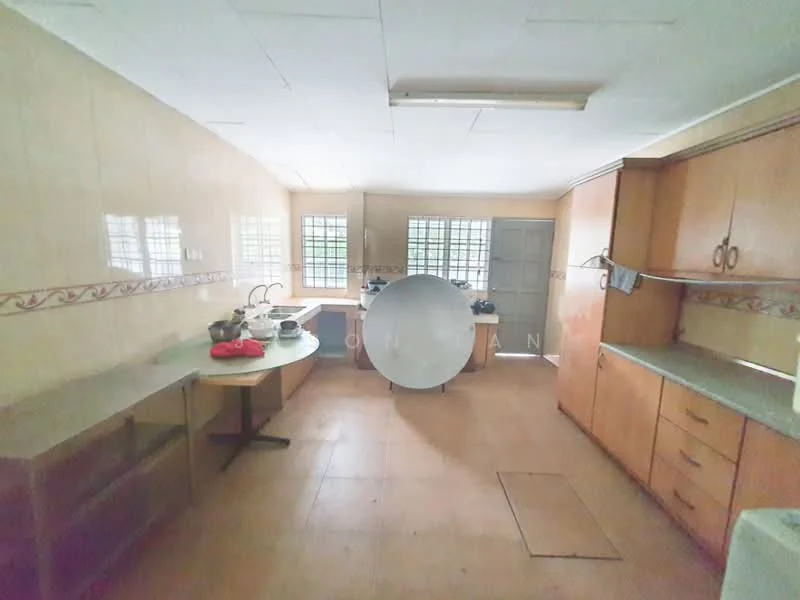 Kitchen features: light beige tiled walls, cream laminate cabinetry, grey countertop, round dining table, stainless-steel sink, single-bowl sink, window with metal grille, floor tiles, kitchen appliances visible, open layout, wall-mounted cabinets, kitchen utensils on table.
