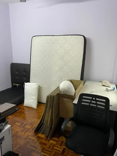 Room features: purple painted walls, parquet wood flooring, black sofa, mattress propped against wall, cardboard boxes, white pillows, desk with chair, office chair.