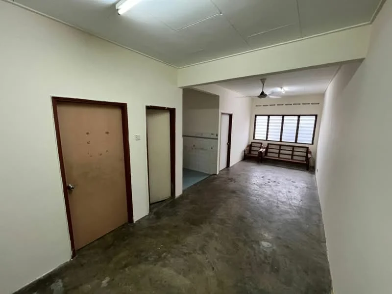 Room features: plain white walls, concrete flooring, single ceiling light fixture, two wooden doors, window with horizontal slats, open layout, corner space for furniture, no visible decor; style: minimalist.