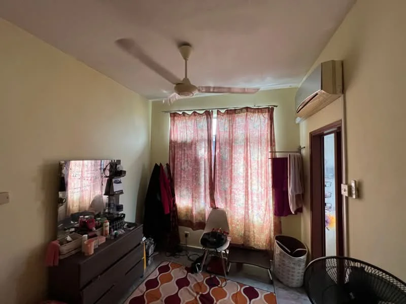 Bedroom features: yellow painted walls, ceiling fan, wall-mounted split AC, two large windows with floral curtains, wooden dresser, mirror on dresser, area rug with geometric pattern, plastic chair, laundry basket, clothing rack, flooring with tiles.