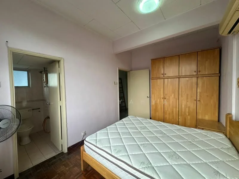Bedroom features: wooden flooring, light purple painted walls, built-in wooden wardrobe, single bed frame, mattress, ceiling light, wall-mounted air conditioning unit, fan, doorway leading to bathroom, window with frosted glass, corner of room with staircase visible. Bathroom features: toilet, sink, shower area, tile flooring, white tiled walls.