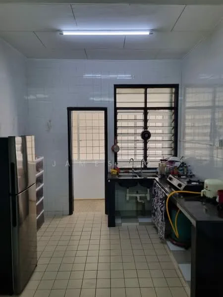 Kitchen features: white tiled walls, grey tiled flooring, stainless-steel fridge, single-bowl stainless-steel sink, chrome pull-down faucet, black countertop, kitchen cabinets with patterned front, window with black metal grille, door leading to another room.