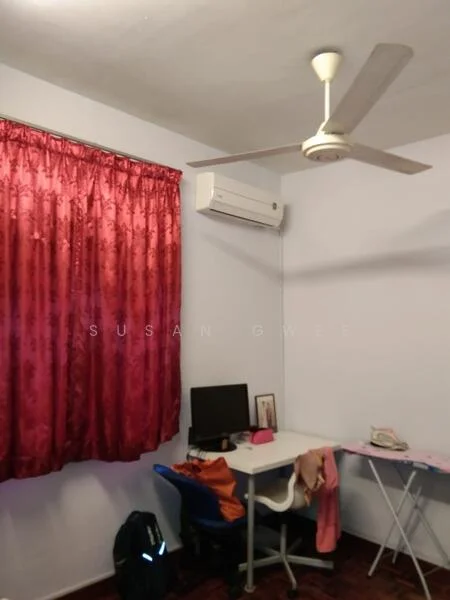 Room features: red curtains, wall-mounted split AC, ceiling fan, desk with chair, computer monitor, ironing board, wooden flooring, light blue painted walls.