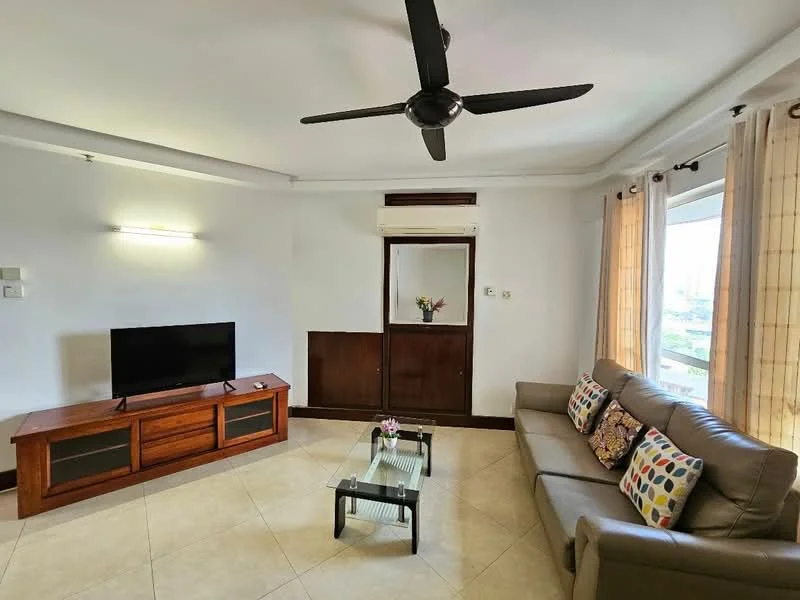 Living features: 3-seater fabric sofa in grey, decorative cushions with colorful patterns, glass coffee table, wooden TV console, wall-mounted TV, ceiling fan, light-colored tiled flooring, curtains with sheer and solid fabric, wall-mounted air conditioning unit, decorative flower vase on console; style: modern; view: city.