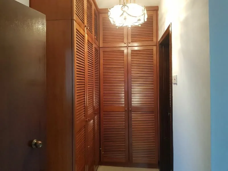 Room features: wooden louvered cabinets, chandelier light fixture, cream wall, tile flooring, dark wood door, light wood cabinetry, built-in storage, neutral color scheme; style: traditional.
