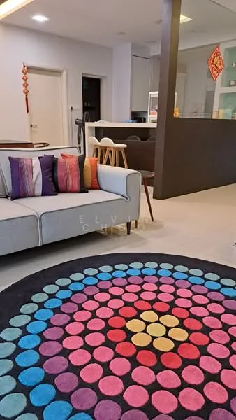 Living features: 3-seater fabric sofa in light grey, decorative cushions in various colors, round area rug with colorful circular pattern, open-plan layout to kitchen, light-colored walls, recessed ceiling lights, wooden dining chairs visible in background, kitchen counter with bar stools visible in background; style: modern.