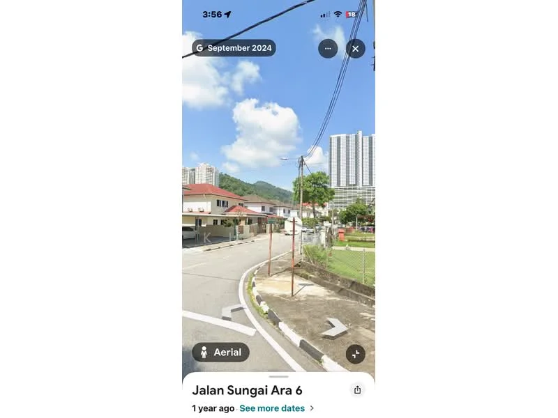 Exterior type: low-rise apartment block; features: surrounded by mature greenery, paved road, street lighting, utility poles, residential buildings in background, clear blue sky, mountain view in background; style: modern.