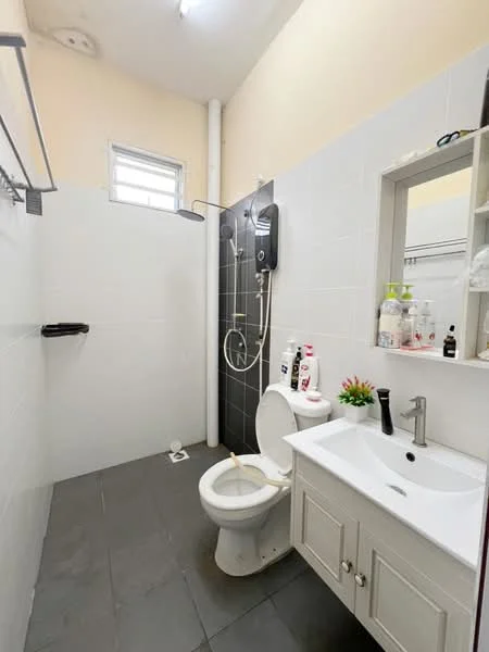 Bathroom features: white tiled walls, black accent wall, grey tile flooring, single-sink vanity with white cabinet, chrome basin mixer faucet, framed mirror, one-piece toilet, shower area with wall-mounted shower head, soap dispenser, toiletries on shelf, small potted plant; style: modern.