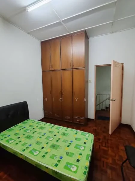 Bedroom features: single bed with green patterned bedding, wooden wardrobe with multiple doors, wooden flooring, white painted walls, ceiling light fixture, door leading to hallway, window with no visible treatment.