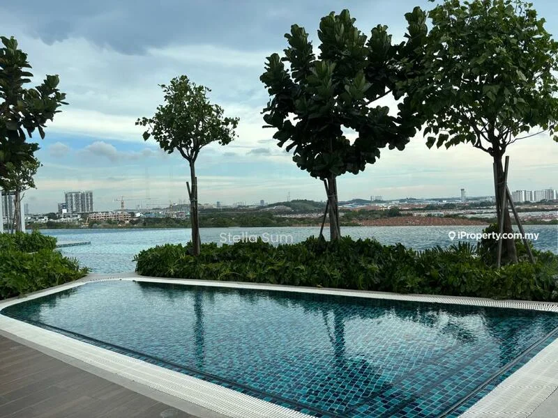 Exterior type: swimming pool deck; features: infinity pool, tiled pool with mosaic pattern, surrounded by landscaped greenery, decorative trees, city skyline view in background, waterfront view, wooden deck flooring, lounge area with seating, manicured plants; style: modern.