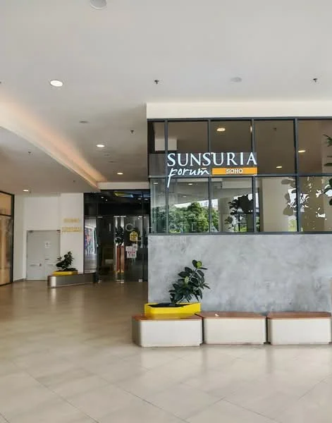 Exterior type: serviced apartment; features: glass facade, entrance with double glass doors, yellow accent signage, grey stone cladding, tiled flooring, indoor plants, seating benches, recessed lighting, high ceiling; style: modern.