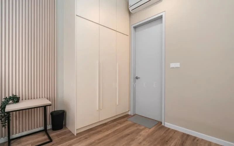 Room features: light wood laminate flooring, cream painted walls, built-in wardrobe with sliding doors, white door, air conditioning unit, small side table, black waste bin, grey doormat, vertical wood panel accent wall; style: modern.