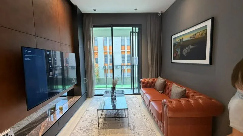 Living features: brown leather chesterfield sofa, glass coffee table, wall-mounted flat-screen TV, dark wood feature wall, grey painted walls, floor-to-ceiling windows, sheer curtains, area rug with intricate pattern, decorative wall art, green view outside; style: modern; view: garden.