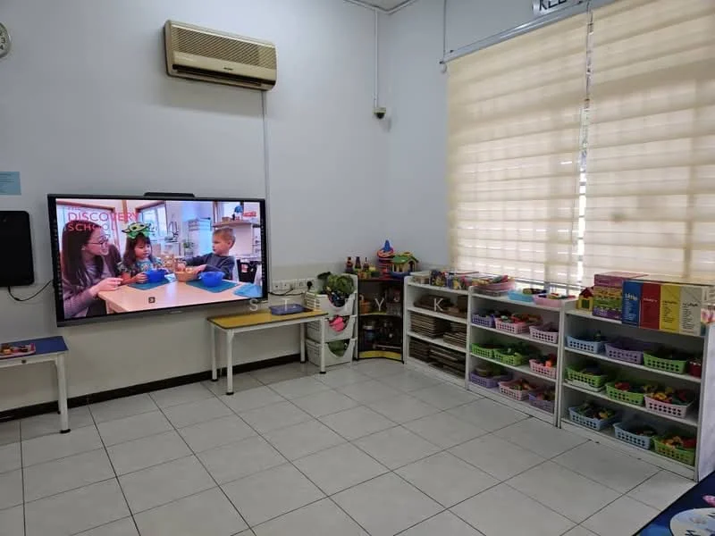 Room features: white painted walls, tile flooring, wall-mounted air conditioning unit, large wall-mounted television, window with sheer blinds, white shelving units, colorful storage bins, children's toys and educational materials; style: modern.