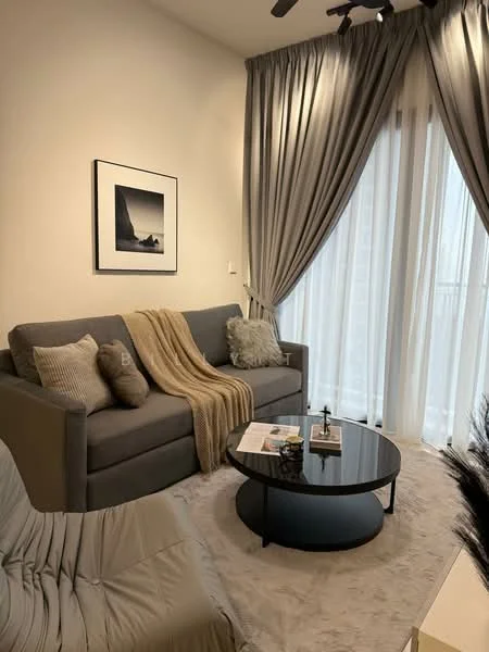 Living features: grey fabric sofa, beige throw blanket, decorative cushions, black round coffee table, framed artwork on wall, floor-to-ceiling sheer curtains, recessed ceiling lights, light-colored area rug; style: modern.
