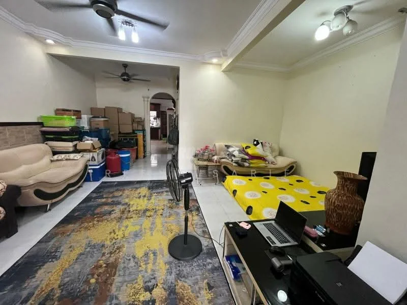Living features: cream painted walls, white ceiling with crown moulding, 5-blade ceiling fan, recessed downlights, 3-seater fabric sofa in beige, yellow patterned mattress on bed frame, area rug with abstract pattern, wooden coffee table, laptop on table, standing fan, boxes stacked in the background; style: traditional.