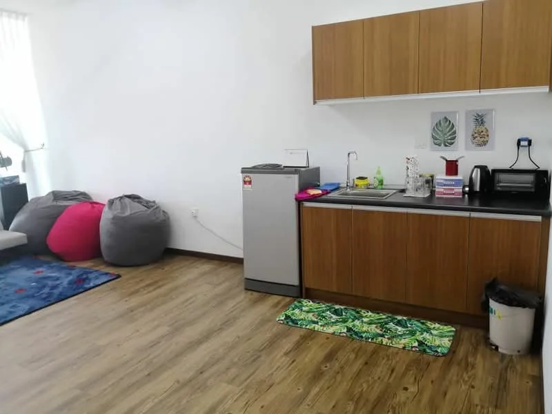 Kitchen features: wood cabinetry, stainless-steel fridge, single-bowl stainless-steel sink, chrome pull-down faucet, countertop with space for appliances, toaster, kettle, microwave, decorative wall art, green patterned mat, laminate flooring, natural light from window, bean bags, area rug; style: modern.