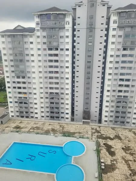 Exterior type: high-rise condominium; features: swimming pool with blue water, two circular children's pools, pool deck with loungers, manicured landscaping, concrete paving around the pool, multiple-storey residential building, balconies on upper floors, glass windows, grey and white facade, visible signage on pool deck; style: modern.