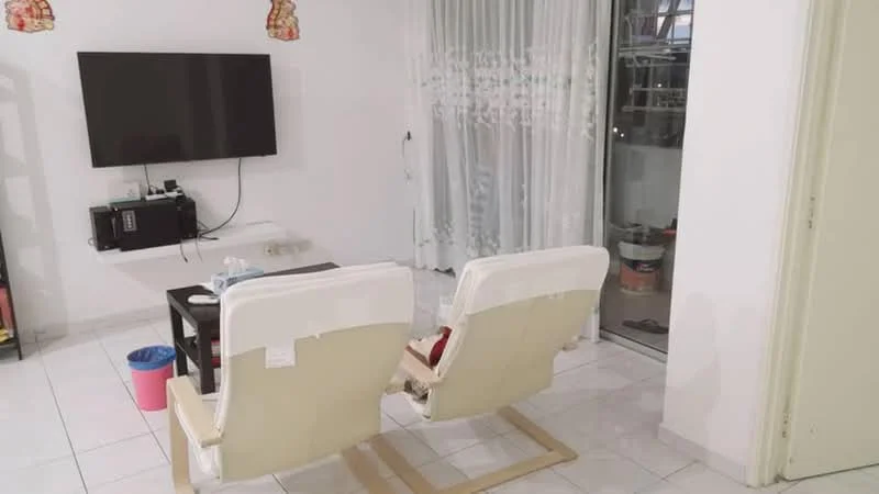 Living features: white painted walls, white sheer curtains, floor-to-ceiling windows, tiled flooring, wall-mounted TV, black TV console, 2 reclining chairs in cream, black coffee table, trash bin, decorative items on console; style: modern.