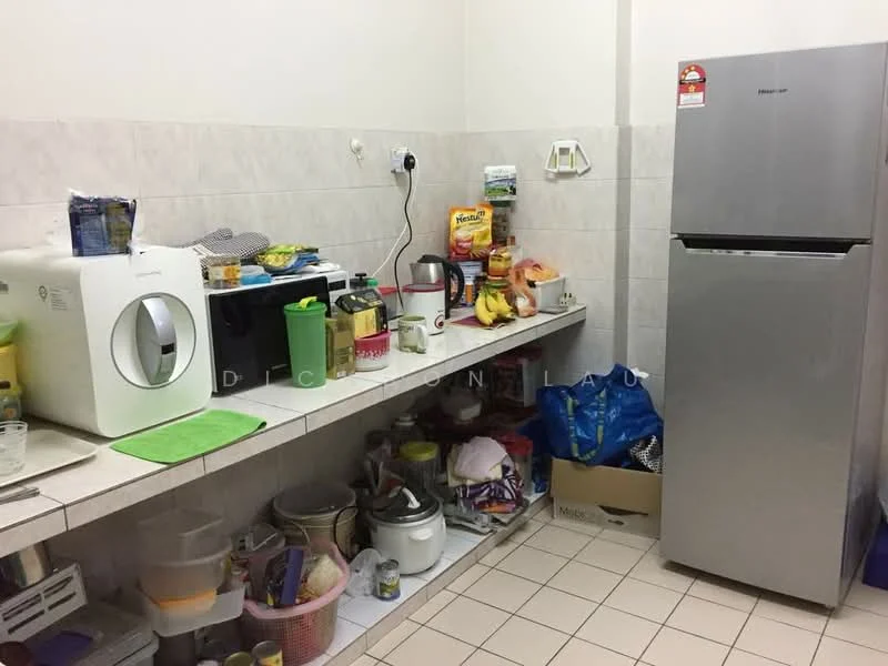 Kitchen features: white tiled walls, light grey tiled flooring, stainless-steel fridge, microwave, toaster, kettle, countertop with storage underneath, various kitchen appliances, fruit bowl with bananas, plastic storage boxes, cleaning supplies, dish rack, cutting board, various food items.