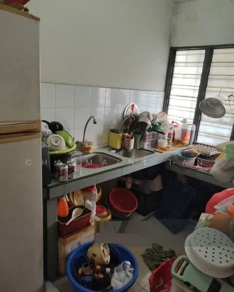 Kitchen features: double-bowl stainless-steel sink, chrome pull-down faucet, white tiled backsplash, grey laminate countertop, wooden cabinetry, various kitchen appliances, plastic storage containers, multiple pots and pans, window with horizontal blinds, floor tiles, cluttered countertop.