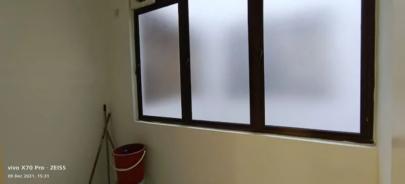 Room features: frosted glass windows, white painted walls, light-colored flooring, clean and minimalistic design, window frames in dark color, clean corner with a mop and bucket; style: minimalist.