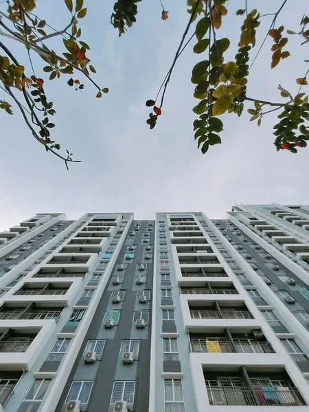 Exterior type: high-rise condominium; features: grey painted facade, balconies with railings, multiple air conditioning units visible, floor-to-ceiling windows, laundry hanging on balconies, approximately 10-storey high-rise; style: modern.