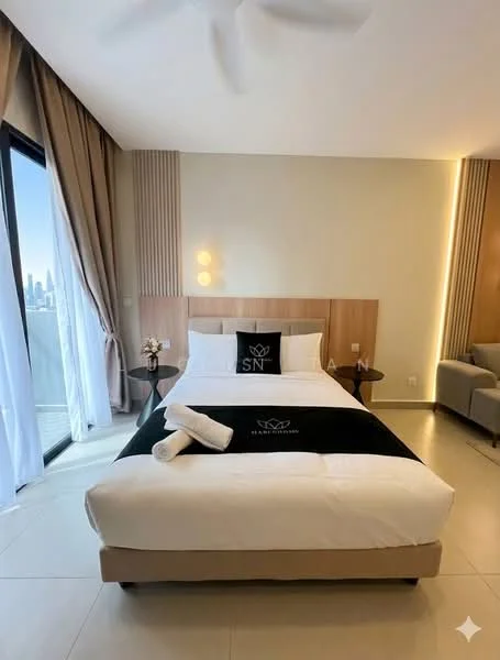 Bedroom features: king-size bed with black and white bedding, upholstered headboard, two white towels on the bed, floor-to-ceiling windows, sheer curtains, grey accent wall, recessed lighting, ceiling fan, side table with wall-mounted light, sofa in grey fabric, decorative wall paneling, tile flooring; style: modern; view: city.