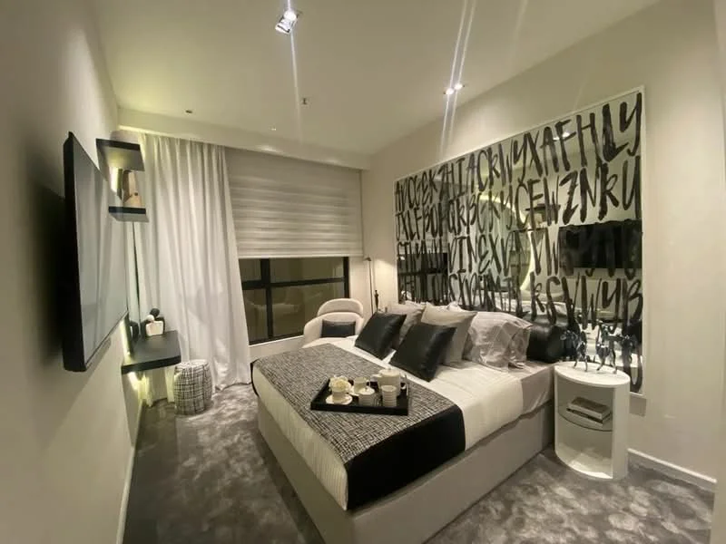 Bedroom features: king-size bed with black and white bedding, upholstered headboard, bedside tables with lamps, wall-mounted TV, decorative wall art with abstract design, sheer curtains, carpet flooring, recessed downlights, accent chair, open shelving unit, decorative accessories on shelves; style: modern.