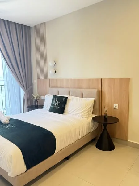 Bedroom features: queen-size bed with upholstered headboard, white bedding with green accent throw, nightstand with round base, decorative pillow with letter 'S', floor-to-ceiling window with sheer curtains, wood panel accent wall, light fixture on wall, small vase with flowers, tile flooring, neutral painted walls; style: modern; view: city.