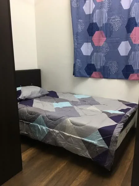 Bedroom features: queen-size bed with patterned bedding, dark wood bed frame, wooden flooring, blue and pink patterned curtains, white painted walls, nightstand with no visible features, small space with limited natural light.