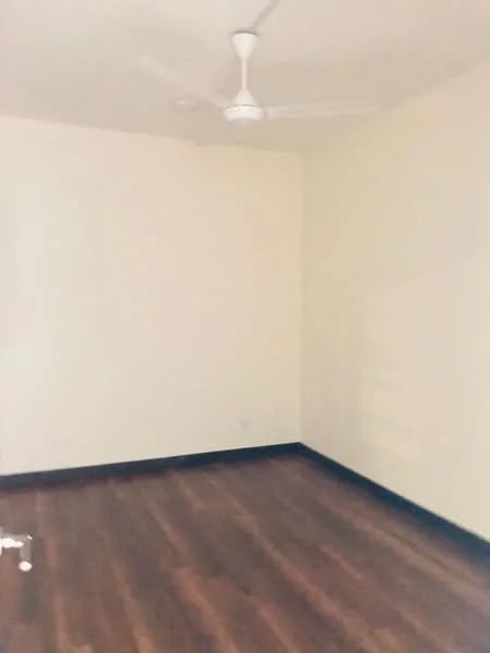 Room features: light brown wooden flooring, white painted walls, ceiling fan.