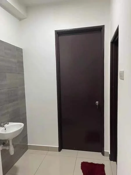 Room features: white painted walls, grey tile accent wall, white floor tiles, brown wooden door, small wall-mounted sink, red bath mat; style: modern.
