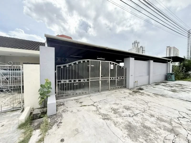 Exterior type: semi-detached house; features: metal gate, concrete driveway, single-storey structure, grey painted facade, overhanging roof, surrounded by greenery, visible city skyline in background; style: modern.