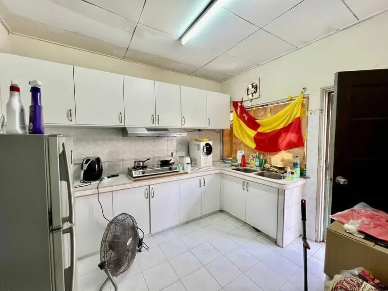 Kitchen features: white cabinetry, stainless-steel fridge, built-in stove, exhaust hood, white tiled backsplash, ceramic tile flooring, double-basin sink, countertop with space for appliances, window with natural light, kitchen flag decoration, fan, washing machine, various kitchen utensils and cleaning supplies.