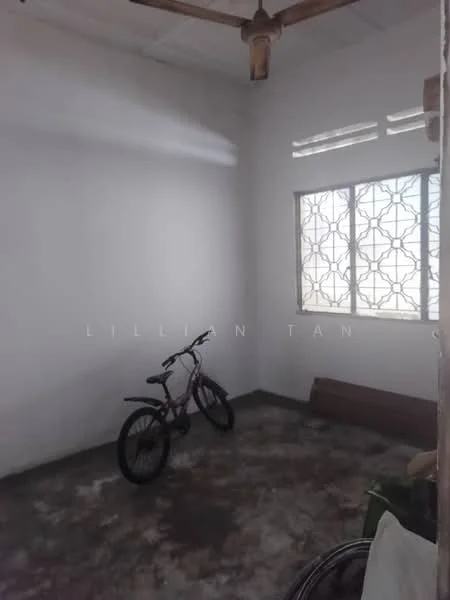 Room features: white painted walls, concrete flooring, ceiling fan, window with decorative grille, bicycle, wooden baseboard, natural light from window.