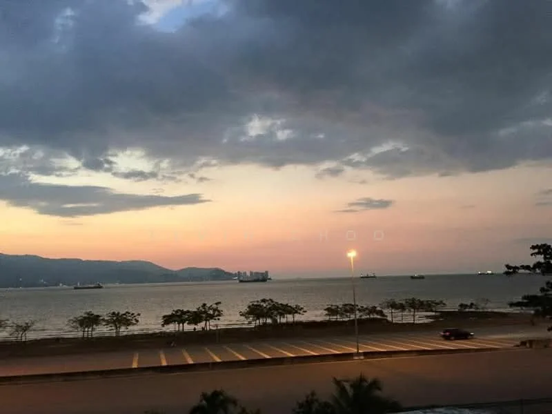 Exterior features: waterfront view, city skyline in background, parking lot, street lamp, trees along the waterfront, cloudy sky, sunset, ships in the water.