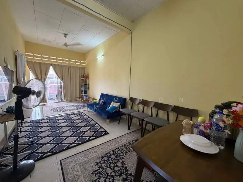 Living features: yellow painted walls, tiled flooring, 5-blade ceiling fan, sofa in blue fabric, wooden dining table, 4 wooden dining chairs, area rug with geometric pattern, decorative flowers in vase, window with sheer curtains, floor fan, wall-mounted light, decorative wall art; style: minimalist.